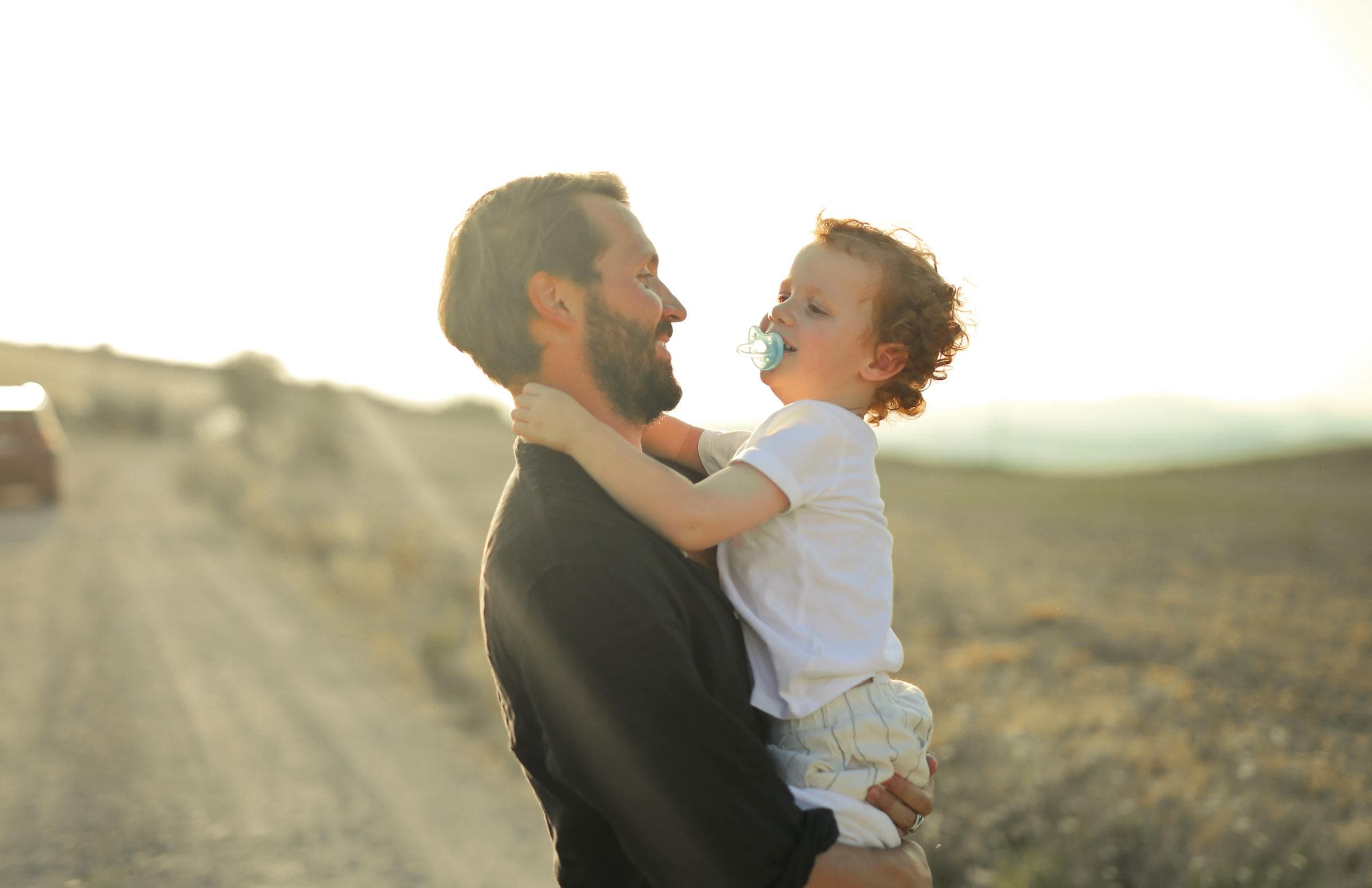 Father embracing his young son at sunset on a quiet country road